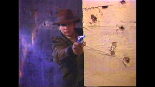 Chris Strompolos as Indiana Jones shoots from cover.
