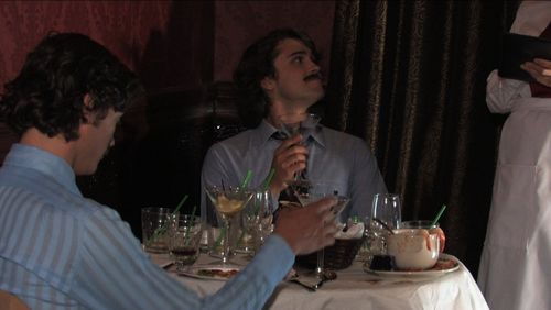 Billy (Sean Carlin), wearing a fake moustache, orders another round of amaretto and pineapple while Paul (Josiah Lipscom