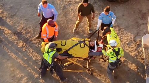 David (John Cho) stands by as rescuers help an EMT (Rene Michelle Aranda) secure Margot (Michelle La) to a gurney in a s