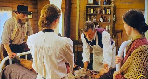 Surgeon Dr. Ned Digby examines injured young Gold Rush miner in Wild West Chronicles.