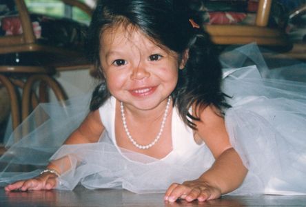 [A sweet Asian-American toddler smiles at the camera, wearing a white dress and pearls.]
